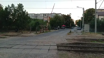 The crossing looking towards the flats — barrier up, road quiet, wires overhead