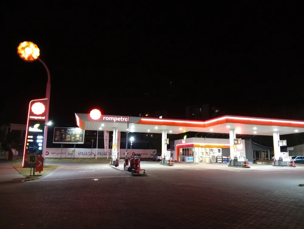 A Rompetrol forecourt after dark — lit canopy, shop open, nobody on the pumps