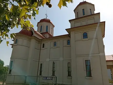Biserica Eroii Neamului in Craiova seen from Calea București — rendered walls, red-tiled towers, the street sign on the fence