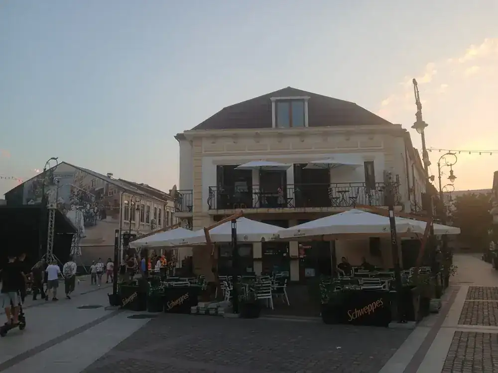 Turned again: the corner house with its balcony, parasols filling the paving, and a painted wall down the side street