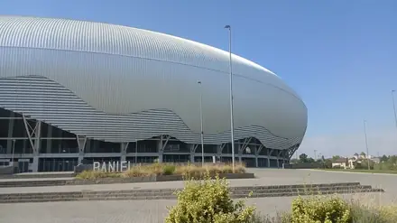 The curved aluminium shell of the Ion Oblemenco Stadium in Craiova seen from the forecourt