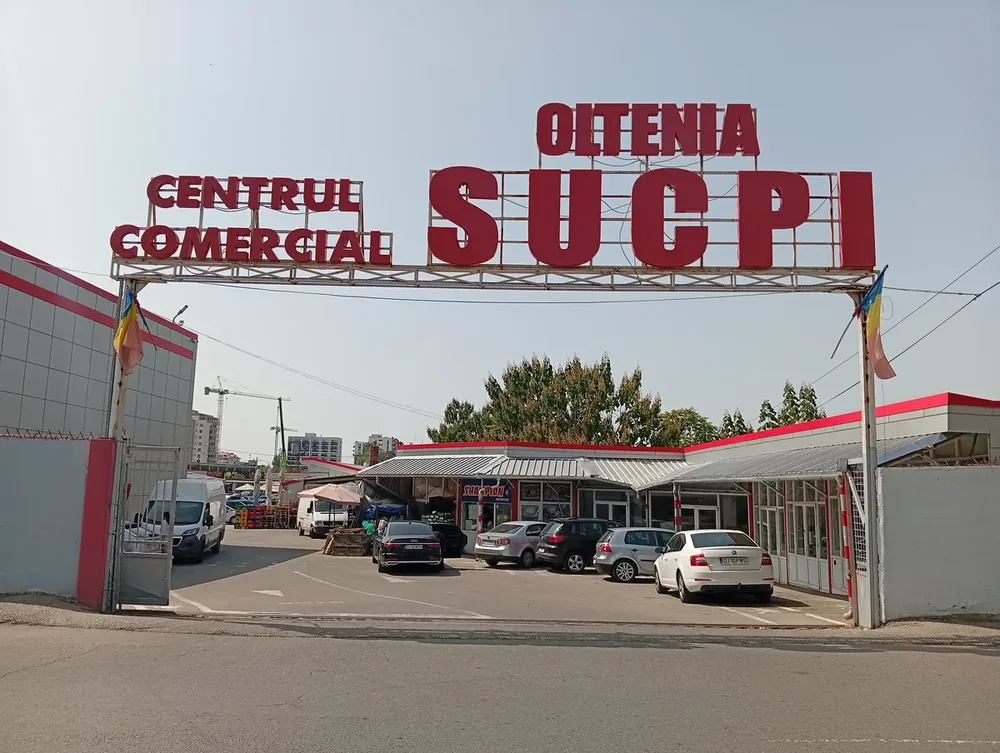 The gantry sign over the entrance, Romanian flags either side