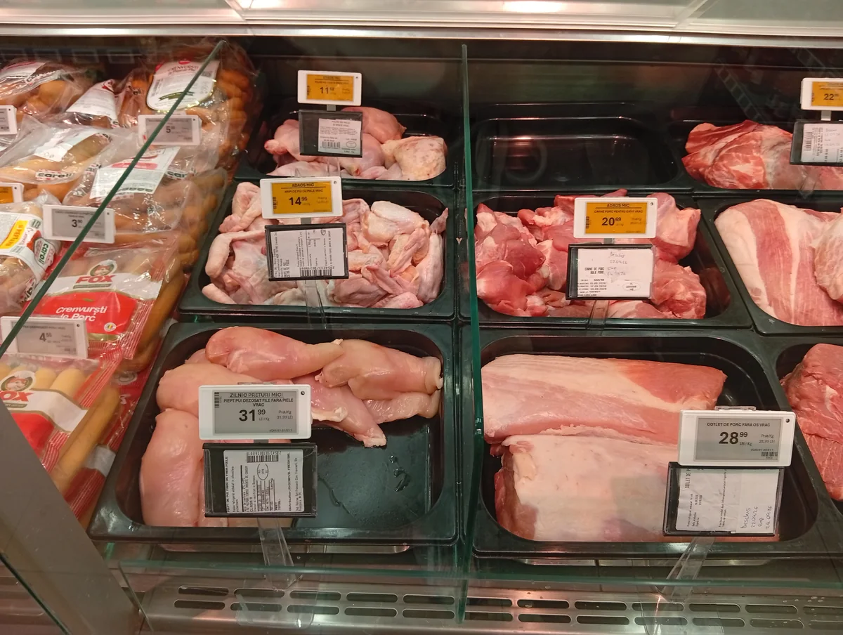 Chicken and pork counter — the yellow “Adaos mic” tags mark the shop’s low-markup line