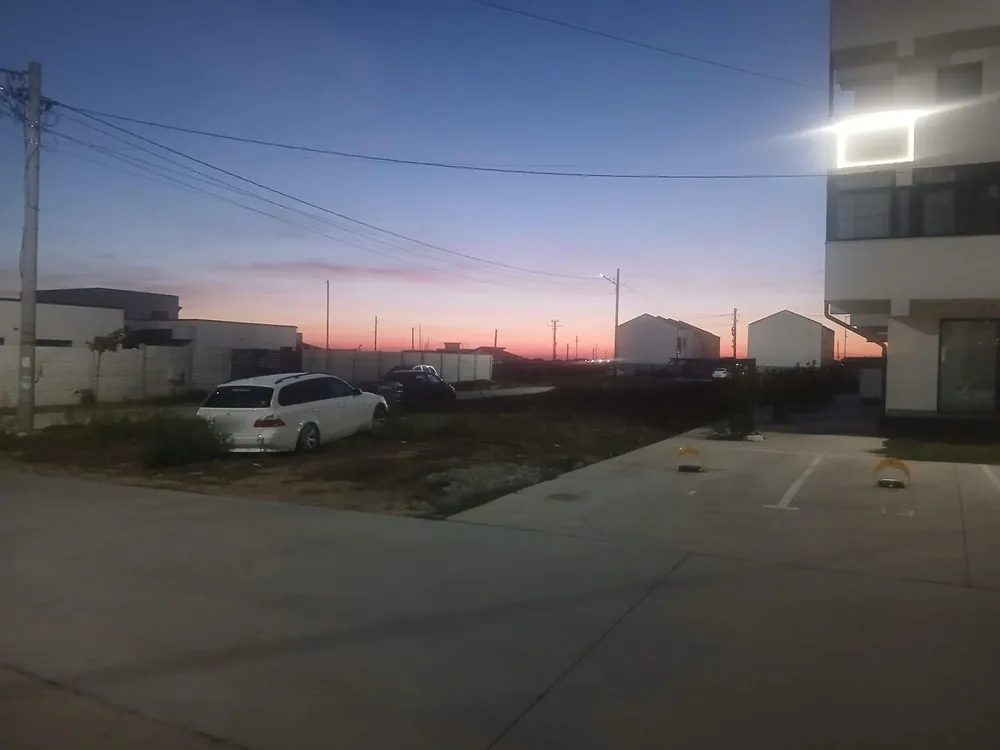 Dusk at the south-east corner of Craiova airport: a pink sky low over the fields, new houses and parked cars in front