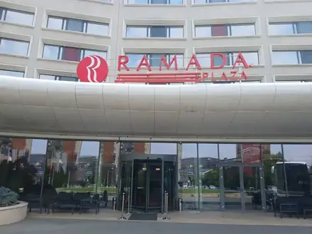 The entrance of the Ramada Plaza Craiova under its curved canopy, red RAMADA PLAZA sign above